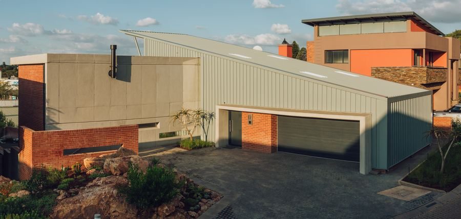 House with a sloping roof, a brick base and a double garage on a paved drive.
