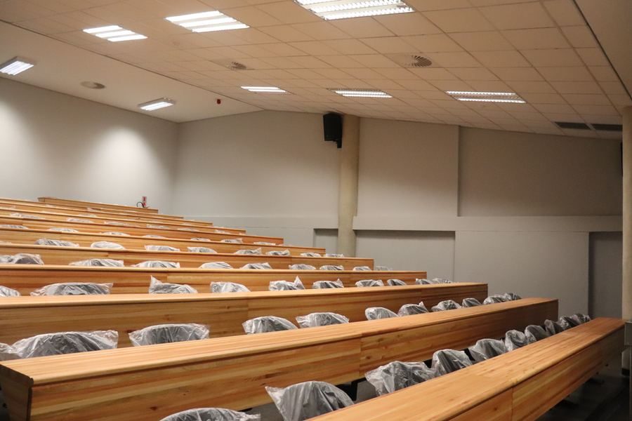 Tiered lecture venue with timber benches and a stepped aisle.